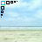 A static beach scene with light blue sky, scattered clouds, and a sandy shore, featuring a corner pattern of black and blue squares.