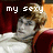 Pixelated image of a person with light brown hair reclining in red theater seats, wearing white clothing and displaying text overlays.