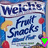 Welch's Fruit Snacks packaging with blue background, red fruit shapes, and yellow crescent shapes, featuring a green and pink pixelated overlay on the lower-left