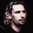 Pixelated static image of a person's face with long hair and beard against black background, rendered in low-resolution style typical of early 2000s digital art.