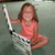 A young girl in a coral sleeveless top sits holding a white and black tennis racket, with purple text overlays changing across frames.