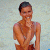 A pixelated image of a person with short dark hair wearing a white top and brown bottoms, standing against a light background next to green text reading 'Original Icons .com'.