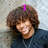 A person with curly brown hair wearing a dark shirt and necklace appears in four with changing text above their head