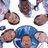 Pixelated image of multiple people in a group photo with blue text overlays listing names on a solid blue background.