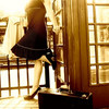 A pixelated anime-style figure in a black dress sits on a railing, legs crossed, with a wooden structure and grid-patterned windows in the background.