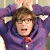 A pixelated figure with brown hair wears a purple jacket over a red shirt, hands raised near head against blurred background.