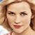 A pixelated close-up of a person with light brown hair, fair skin, and red lips, wearing a light-colored top with a red strap visible on the shoulder.