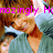 Pixelated image of a person with brown hair wearing a teal shirt and brown jacket, with pink text overlay reading "mozingly Have Zod Ef".