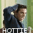 Pixelated image of a person in dark clothing with a light-colored collar, standing against a green and beige background with the word HOTEL in white block letters at the bottom.