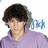 Pixelated image of a person with dark curly hair wearing a purple shirt, blue text 'DM' visible to the right.