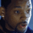 Pixelated close-up of a person's face with brown skin tone, visible eye, nose, mouth, and ear, against a blue background with dark and light areas.
