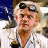 Static 48x48 pixel icon depicting a character with light brown hair, dark sunglasses, and a white lab coat against a blue background.