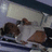 Animated sequence showing a character in a white shirt and brown pants lying on a bed with striped sheets, head turning left to right.