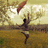 Pixelated figure in mid-air with arms raised, holding a long red object against a bright sky and grassy field background.