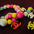 Pixelated animated icon with pink, yellow, and orange shapes forming a stylized figure against dark background; small pink heart appears at bottom center.