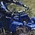 Animated sequence showing a blue ATV with rider navigating grassy terrain, transitioning from close-up to wider view.