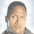 Pixelated static image of a person's face with short dark hair, light skin tone, and neutral expression against a gradient background.