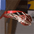A pixelated red and white object with a curved shape rests on a brown vertical structure against a gray background with blue and yellow elements.