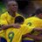 Pixelated static image of two soccer players in yellow jerseys with green accents, one wearing number 9, embracing on a field.
