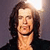 Pixelated portrait of a person with long brown hair, light skin, and a black top against a gradient background.