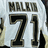 White sports jersey with black and gold text displaying 'MALIK' above number 71, visible on a of repeated images