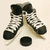 Pixelated image of two ice hockey skates and a black puck on light background, rendered in grayscale with visible pixelation.