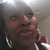A static pixelated image shows a person with dark skin wearing large hoop earrings and red lipstick, smiling slightly against a blurred background.