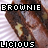 Brownie-shaped object with visible nuts, held by a hand against striped background; text "BROWNIE" and "LICIOUS" in pixelated font.
