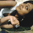 Pixelated image of a person in dark clothing holding another figure with light skin and short hair, set against a blurred background.
