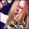 A woman with long blonde hair and red cheeks appears in two side-by-side frames, mouth open as if shouting or singing.
