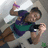 Pixelated figure in dynamic pose with raised arm holding purple object, wearing dark blue and green outfit against gray background.