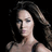 Pixelated close-up of a person with long dark hair against a black background, wearing a dark strapless top.
