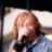 Pixelated static image of a person with light brown hair wearing dark clothing against a bright background.
