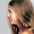 Pixelated profile view of a person with light brown hair and a black top against a light gray background.