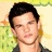 A person with dark hair and a dark shirt appears in a of four with a green and yellow background