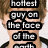 A pixelated image of a person with brown hair and blue eyes, wearing a black-and-white collared shirt, overlaid with stacked text blocks reading "hottest guy on the face of the earth".