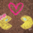 A static pixelated image shows two yellow cartoon characters with blue eyes and pink bows, positioned below a pink heart outline on a brown background.