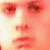 Pixelated close-up of a face with reddish skin tones, featuring two eyes, a nose, and lips in a neutral expression.