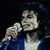 Static pixelated image of a person singing into a microphone with dark hair and blue clothing against black background.