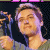 A pixelated contact sheet showing two frames of an animated icon featuring a person holding a microphone on the left and green text reading "Original Icons .com" on the right against a dark background.