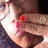 Pixelated close-up of a person's face with a bright light source on the left, red mark on the cheek, and dark clothing visible.