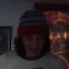 A person wearing a red and blue striped beanie and light-colored shirt appears in two with hands raised in front of their face