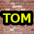 Static pixel art icon with bold yellow text 'TOM' on a black background, set against a blurred brick wall pattern.
