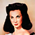 Static pixelated image of a woman with dark shoulder-length hair, fair skin, and red lips against a light background.