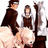 Two pixelated figures in dark brown outfits stand side-by-side with a tall staff, one figure has blue text overlay.