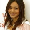 A person with long brown hair wearing a light pink jacket over a white shirt, standing against a white background with partial red text.