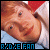 Pixelated image of a person with red hair wearing a white shirt and blue background, text "R2D2E FAN" in blue at bottom.