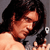 Static pixelated image of a person with long dark hair and light skin, cropped to show upper body against gray background.