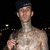 Pixelated static image of a shirtless person with dark hair against a black background, featuring a small yellow light on the left side.