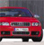 Red car with dark blue roof, white headlights, and visible license plate against gray background.